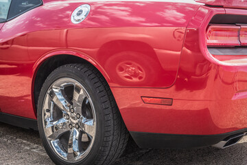 Fototapeta na wymiar Red muscle car's chrome wheel close up