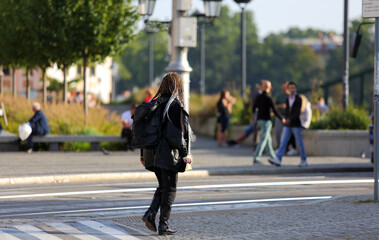 Piękna kobieta, dziewczyna z plecakiem spaceruje po chodniku, deptaku we Wrocławiu.	
