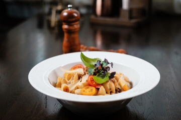 Pasta with tomatoes served on restaurant table. Traditional Italian dish.