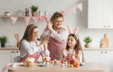Happy family, mom and her daughters rejoice and clap their hands while preparing for