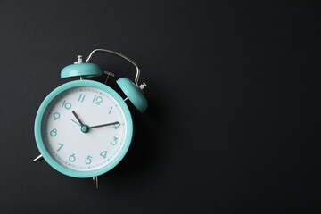 Alarm clock and space for text on black background, top view. School time