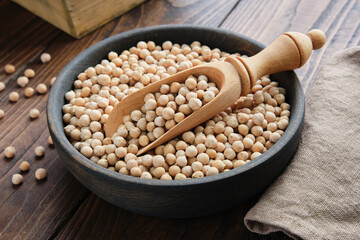 Raw chickpeas in bowl. Chickpeas in bowl and scoop on wooden table.