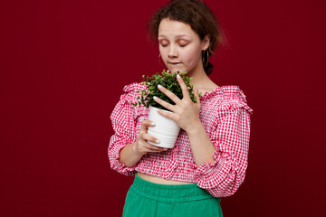 beautiful woman in pink blouse is posing with a plant in white pot close-up