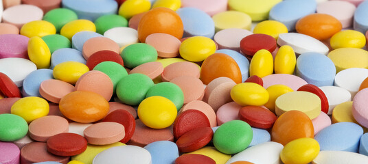 Pile of medical pills in yellow, green and other colors.