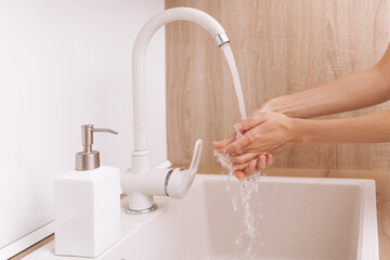 Washing hands under the flowing water tap. Washing hands rubbing with soap for corona virus prevention, hygiene to stop spreading corona virus in or public wash room. Hygiene concept hand detail