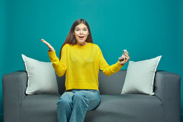 Excited happy shocked young girl hold gift box with engagement ring surprised by marriage proposal, sitting on sofa