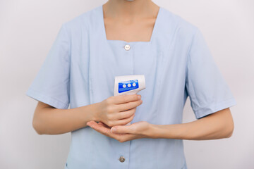 Temperature measurement gun in doctor hands. Close-up shot of doctor wearing protective surgical...