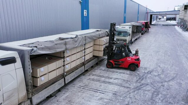 A loader is loading chipboard packages into the truck at the factory