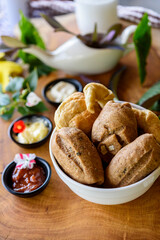 Homemade Brazilian wholegrain breads in a white bowl on a blurred wooden background.