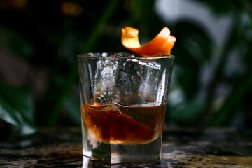 Old fashioned whiskey cocktail in glass with clear ice and orange twist 