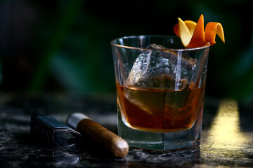 Old fashioned whiskey cocktail in glass with clear ice and orange twist 