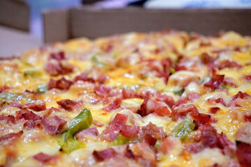 Cooked ham, sausage and cheese pizza on a cardboard box