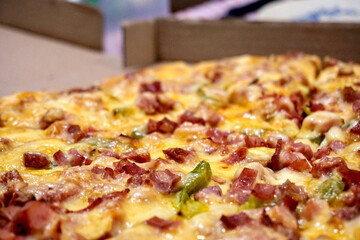 Cooked ham, sausage and cheese pizza on a cardboard box