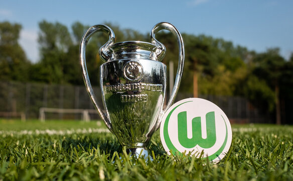 August 30, 2021 Wolfsburg, Germany. The emblem of the football club VfL Wolfsburg and the UEFA Champions League Cup on a green lawn.