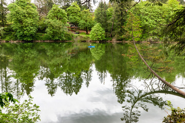 Round lake in Washington state with shimmery reflective water and lush green trees surrounding lone kayaker on a beautiful summer day.