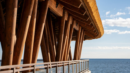 Fototapeta premium Restaurant gazebo with a thatched roof on the seashore. Summer house of café on the beach 