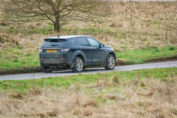 Fototapeta premium a black land rover discovery sport driving along a country road
