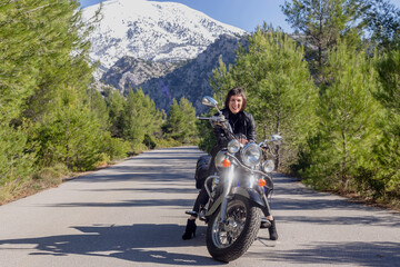 Young beautiful Greek woman sitting on a motorcycle close-up