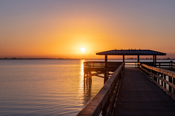 Fototapeta na wymiar Sunrise over the pier in Safety Harbor, Florida reflecting in Tampa Bay.