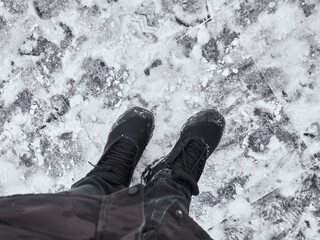Feet on the background of snow-covered paving stones. Men's shoes