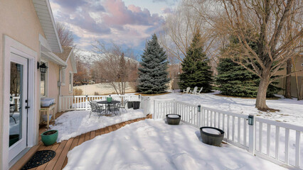 Panorama Puffy clouds at sunset Snow covered deck of a house with white railing and wood planks