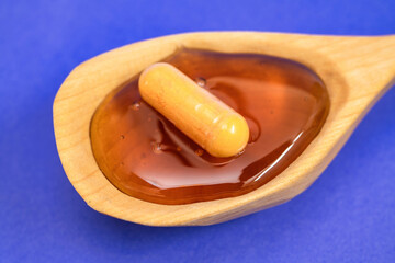 Concept of natural medicine, a pill is seen over honey