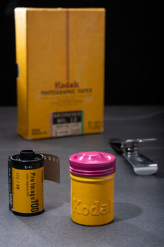 Vintage 35mm tin film canister and photographic paper from the 1070s and modern film cartridge labelled with Kodak Eastman logo.