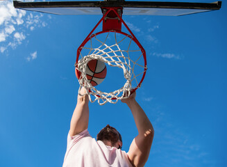 young man with basketball ball on court. professional basketball player training outdoor. © Olena