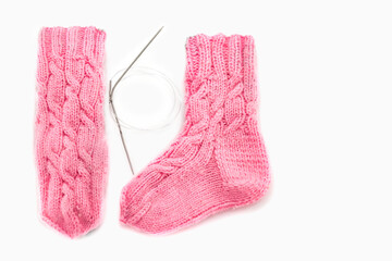 Pink knitted socks with Aran pattern and knitting needles on a white background. Place for text....