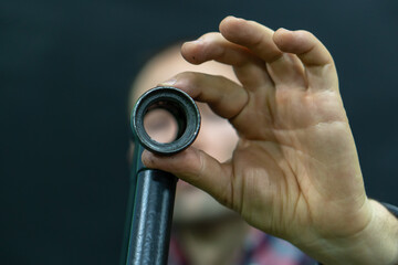 A bicycle mechanic in the workshop holds a frame from an old bicycle in his hands. Checking bicycle parts for wear, replacing broken parts. The face of a guy in a shirt on a black background