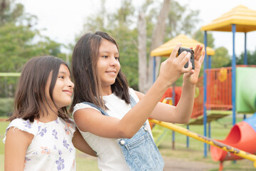 
friends and sisters taking selfie with smartphone, in park in the afternoon on vacation