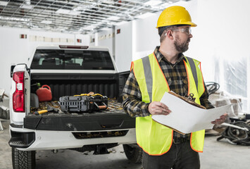 Construction Supervisor with Blueprints in His Hand Next to Pickup Truck Inside Commercial Building © Tomasz Zajda