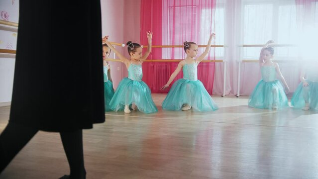 Little ballet girls in blue dresses training in the studio