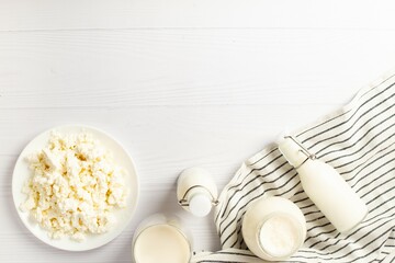 Fresh dairy products, wheat, white wood background, top view