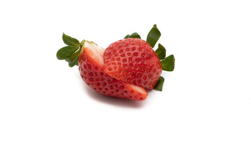 A whole strawberry with its green leaves, cut in half. Isolated on white background.