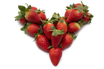 A bunch of whole strawberries with their green leaves, laid out in the shape of a heart. Isolated on white background.