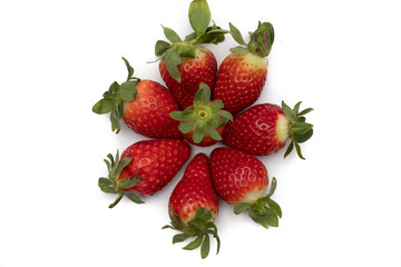 A handful of whole strawberries with their green leaves laid out in a star shape. Isolated on white background.