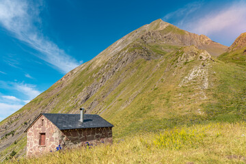 Fototapeta na wymiar Beautiful mountain landscape with a tiny house. Scenic view of a colorful sky above the mountains. Adventure travel concept.