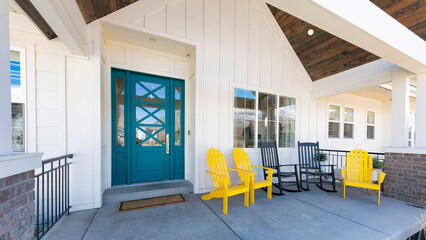 Panorama Porch of a house with blue green door and lounge chairs