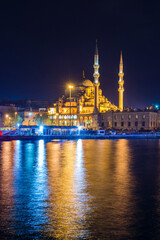 Obraz premium Reflection of New Mosque (New Valide Sultan Mosque) in the Golden Horn at night, Istanbul, Turkey, Eastern Europe