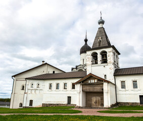 Wide panoramic view of Ferapontovo orthodox monastery in Vologda region, northern Russia. White cathedral and bell tower walls, green grass, sky with clouds