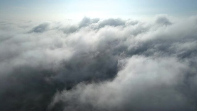 Aerial shot of flying over a layer of soft clouds at dawn