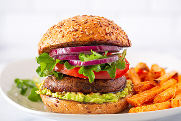 Healthy meat alternative portobello mushroom veggie burger on a whole grain bun against a light...