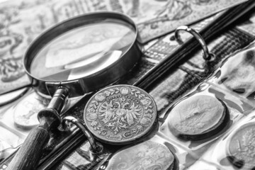 Numismatics. Old collectible coins made of silver on a wooden table.Coins in the album.Collection of old coins. Magnifying glass