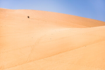 Couple climbing sand dunes at Huacachina, a village in the desert, Ica Region, Peru, South America