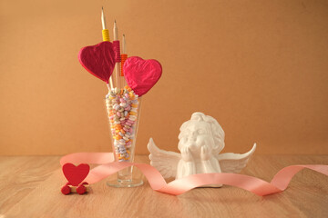 romantic still life in love style, in a glass vase red hearts on sticks, colorful candies, concept...
