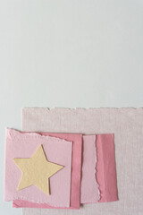 torn and cut pink paper shapes with pale yellow paper star 
