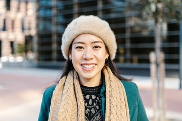 Portrait of young asian woman smiling at camera - Happy chinese female entrepreneur standing in city street