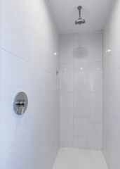 Vertical Narrow white shower room with white glossy tile surround