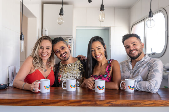 LGBT people with rainbow mugs posing on the counter in the kitchen. 
